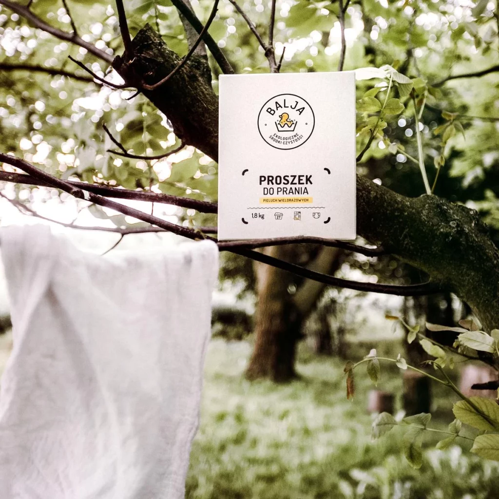 Proszek do prania pieluch wielorazowych i wisząca na drzewie pieluszka